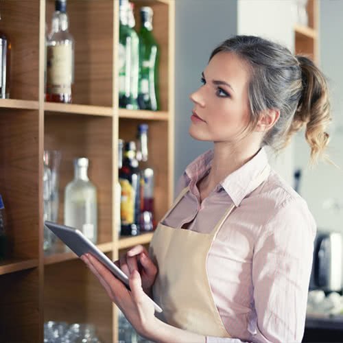 bar employee taking inventory of liquor bottles