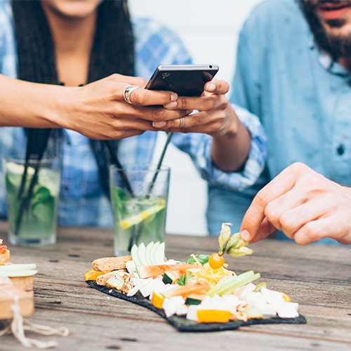 Female taking photo with phone of dish at a restaurant