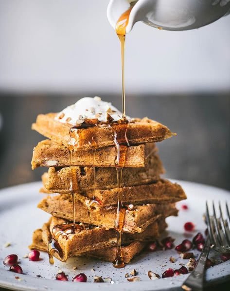 Syrup being poured on a stack of waffles